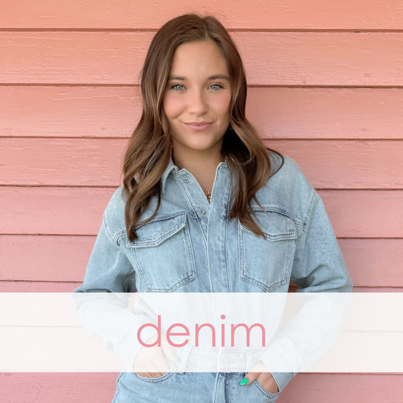 A young woman with wavy brown hair poses against a pink wooden wall, wearing a light-wash denim jumpsuit with front pockets and a belted waist. "Denim" is overlaid in soft pink text, showcasing a chic, modern take on classic denim style.