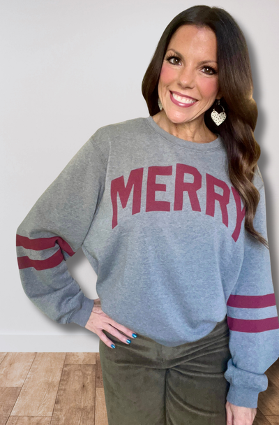 Woman wearing a gray sweatshirt with 'MERRY' in red text, standing against a plain background.